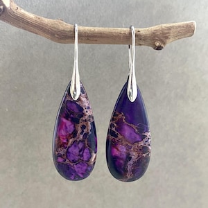 May include: A pair of silver teardrop earrings with purple and brown marbled stone accents.