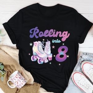May include: Black t-shirt featuring a graphic of roller skates and the text "Rolling into 8".