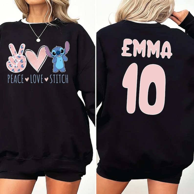 May include: Black sweatshirt with a peace sign, heart, and Stitch character on the front. The back of the sweatshirt has the name "EMMA" and the number "10" in pink.