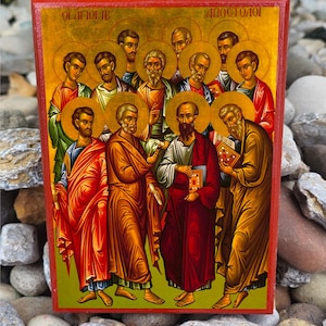 May include: A hand-painted icon depicting the twelve apostles of Jesus Christ. The icon is on a wooden panel with a red border and gold background. The apostles are depicted in a circle around Jesus, who is in the center. The icon is titled "Οι ΑΓΙΟΙ ΑΠΟΣΤΟΛΟΙ" in Greek, which translates to "The Holy Apostles".