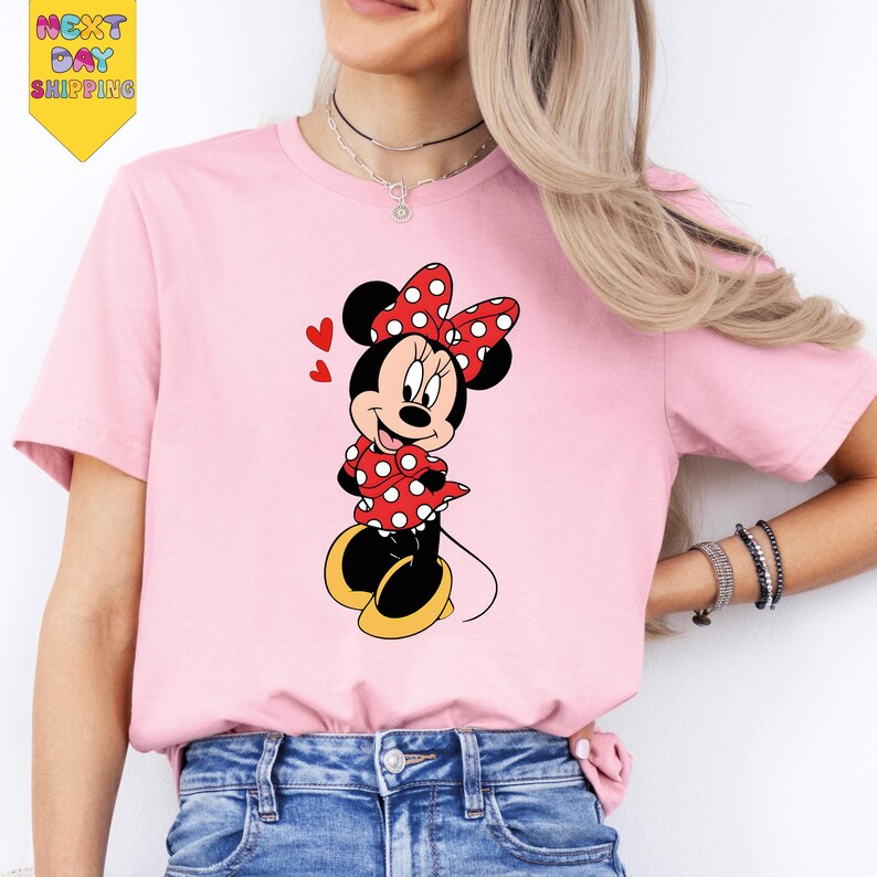 A woman wearing a pink t-shirt with a Minnie Mouse graphic printed on it.