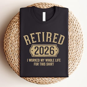 A black t-shirt with a graphic design that says "RETIRED 2026 I WORKED MY WHOLE LIFE FOR THIS SHIRT" printed on it.