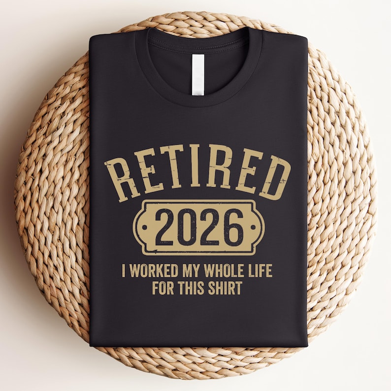 A black t-shirt with a graphic design that says "RETIRED 2026 I WORKED MY WHOLE LIFE FOR THIS SHIRT" printed on it.