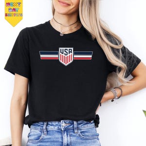 A woman wearing a black t-shirt with a graphic of the United States flag and a black and red striped design.
