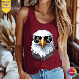 A woman wearing a red tank top with a graphic of an eagle wearing sunglasses and the text "GAME DAY" printed on it.