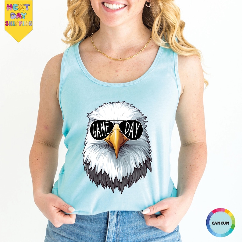 A woman wearing a light blue tank top with a graphic of an eagle wearing sunglasses and the text "GAME DAY" printed on it.