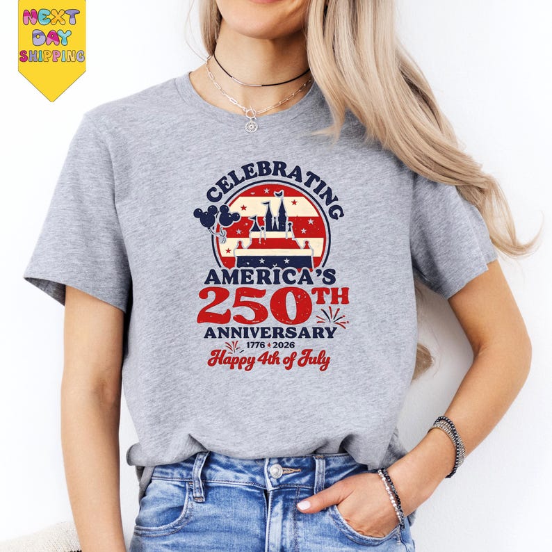 A woman wearing a gray t-shirt with a graphic design celebrating America's 250th anniversary.