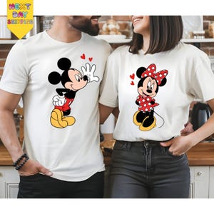 A man and a woman are standing close together, both wearing white t-shirts with Mickey Mouse designs.
