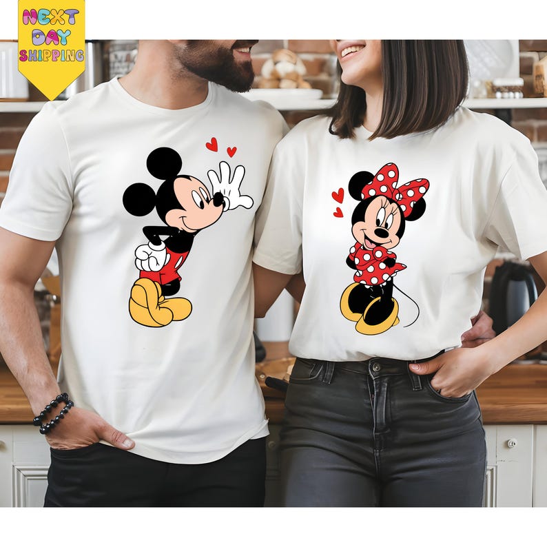 A man and a woman are standing close together, both wearing white t-shirts with Mickey Mouse designs.