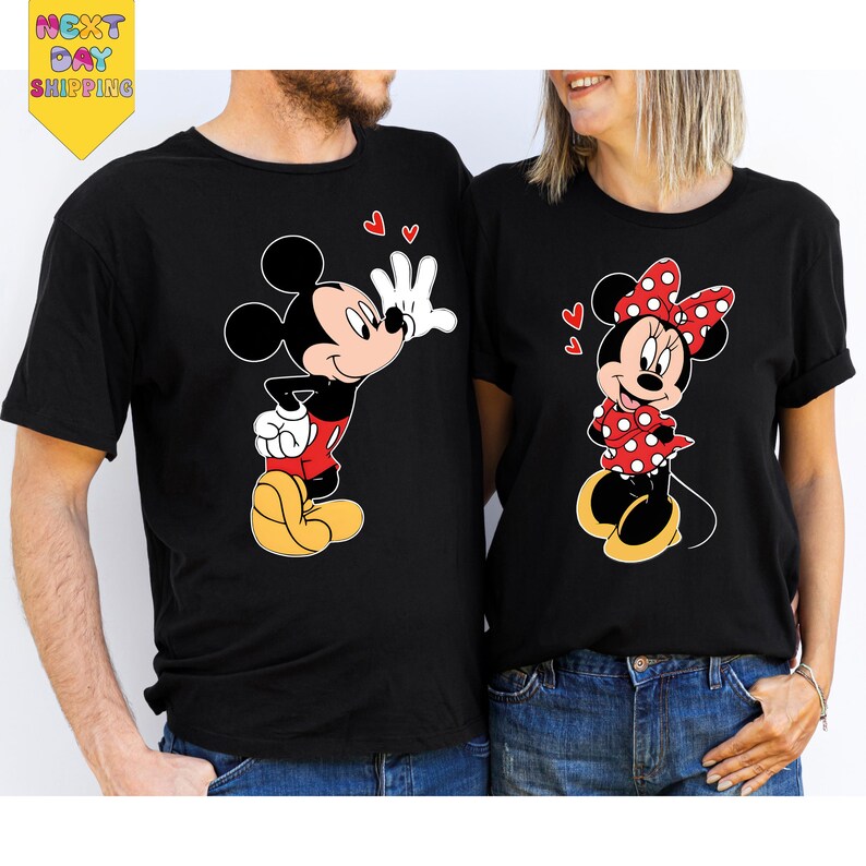 A man and a woman are standing next to each other, both wearing black t-shirts with Mickey Mouse designs.