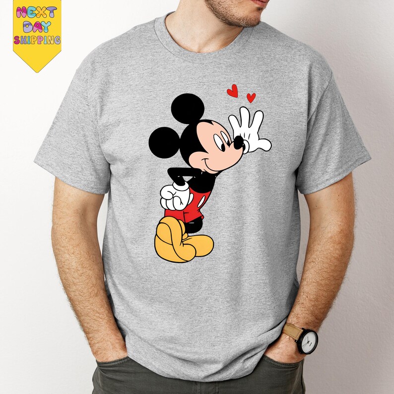 A man wearing a gray t-shirt with a cartoon image of Mickey Mouse and a heart symbol.