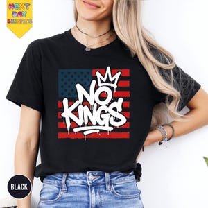 a woman wearing a black t - shirt with the words no kings on it
