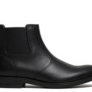Pode incluir: Bota Chelsea de couro preto com bico redondo e pain&eacute;is laterais el&aacute;sticos. A bota de tornozelo apresenta uma aba na parte de tr&aacute;s e um salto baixo. A bota &eacute; feita de couro texturizado.