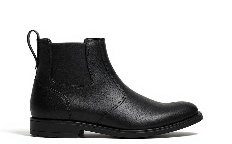 Pode incluir: Bota Chelsea de couro preto com bico redondo e pain&eacute;is laterais el&aacute;sticos. A bota de tornozelo apresenta uma aba na parte de tr&aacute;s e um salto baixo. A bota &eacute; feita de couro texturizado.
