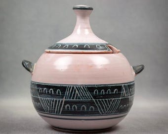 May include: A pink ceramic sugar bowl with a lid. The bowl has a black and white geometric design.