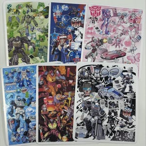 May include: A collection of six rectangular stickers featuring colorful illustrations of Transformers characters and related imagery. The stickers showcase various robots, vehicles, and icons in vibrant designs, with a white border.