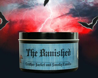 May include: A black tin candle with a blue label that reads "The Banished" and "Leather Jacket and Smoky Vanilla". The candle is set against a backdrop of a stormy sky with lightning and bats.
