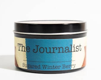 May include: A black tin candle with a label that reads "The Journalist" and "Sugar Winter Berry".