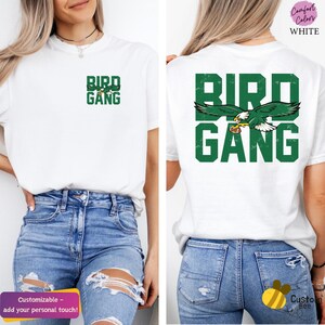 a woman wearing a white bird gang t - shirt