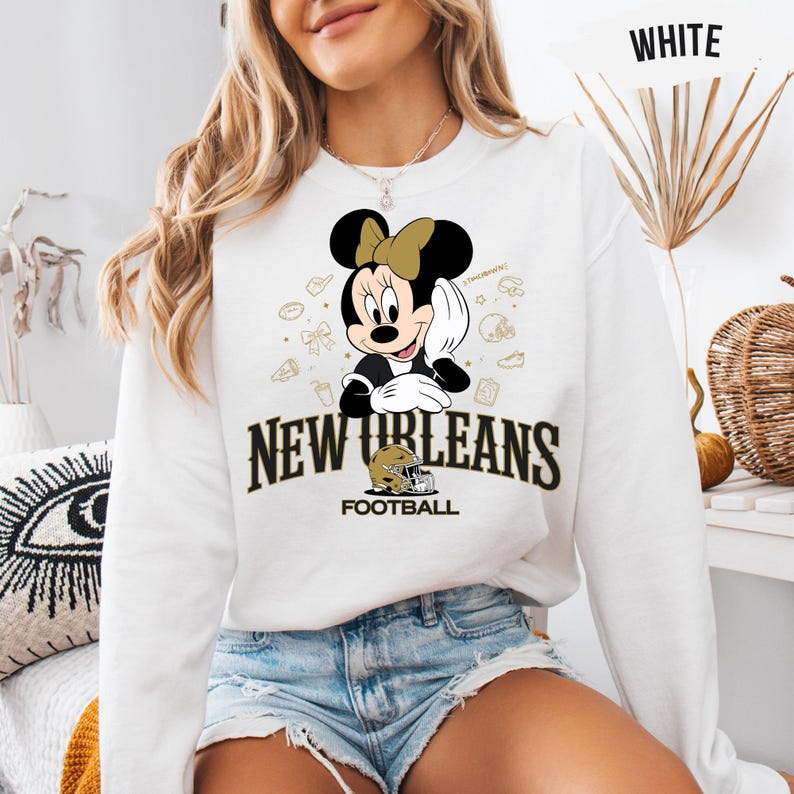 A woman wearing a white sweatshirt with a Minnie Mouse graphic and text that says "New Orleans Football".
