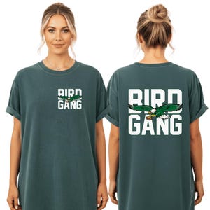 A woman wearing a green t-shirt with the text "BIRD GANG" printed on it.