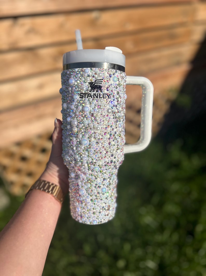 Puede incluir: Una taza de cer&aacute;mica blanca con un asa negra y el texto "But First, Coffee" en negro, con una fuente de estilo manuscrito. La taza est&aacute; sobre una superficie blanca.