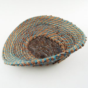 May include: A brown ceramic bowl with a blue woven rim. The bowl has a textured, embossed design on the inside.