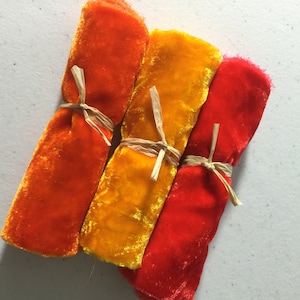 May include: Three rolls of velvet ribbon in orange, yellow, and red colors. Each roll is tied with a natural twine string.