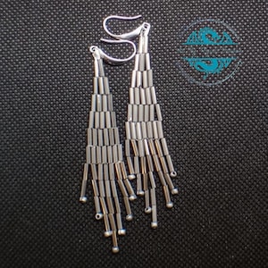 May include: A pair of silver dangle earrings with a cascading design of small, cylindrical beads.