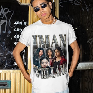 May include: A white short-sleeved crew neck t-shirt featuring a graphic print of Iman Vellani in multiple poses. The text IMAN VELLANI is printed in a metallic, chrome-style font above and below the images, creating a vintage-inspired aesthetic.