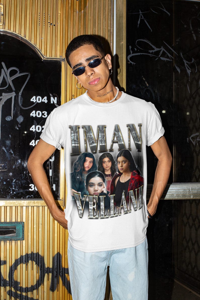 May include: A white short-sleeved crew neck t-shirt featuring a graphic print of Iman Vellani in multiple poses. The text IMAN VELLANI is printed in a metallic, chrome-style font above and below the images, creating a vintage-inspired aesthetic.