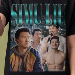 以下が含まれることがあります： 青い文字と緑の文字で「SIMU LIU」と書かれたレトロなグラフィックがプリントされた黒いTシャツ。グラフィックには、カジュアルな服装をした男性3人と、シャツを着ていない男性1人の計4人の男性の画像も含まれています。グラフィックの背景は街並みです。