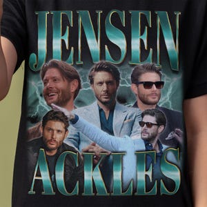 May include: Black t-shirt featuring a collage of images of Jensen Ackles with the text "JENSEN ACKLES" in a teal and gold font. The design includes a lightning bolt background.