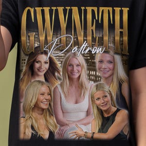 May include: A black t-shirt featuring a graphic print of five photographs of Gwyneth Paltrow. The name GWYNETH is printed in large gold letters at the top, with the name Paltrow written in a white cursive script font over a city skyline background.