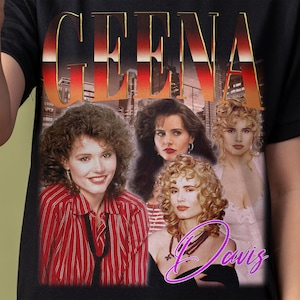 Puede incluir: Una camiseta negra con un gráfico de estilo vintage que presenta el nombre "GEENA DAVIS" en letras doradas grandes. El gráfico también incluye cuatro mujeres con diferentes peinados y ropa.
