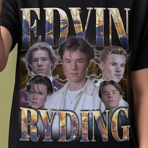 Op de afbeelding: Zwart T-shirt met de tekst "EDVIN RYDING" in een goud- en blauwe gradi&euml;ntkleur. Het shirt heeft een afbeelding van vijf jonge mannen. De achtergrond heeft een bliksemontwerp.