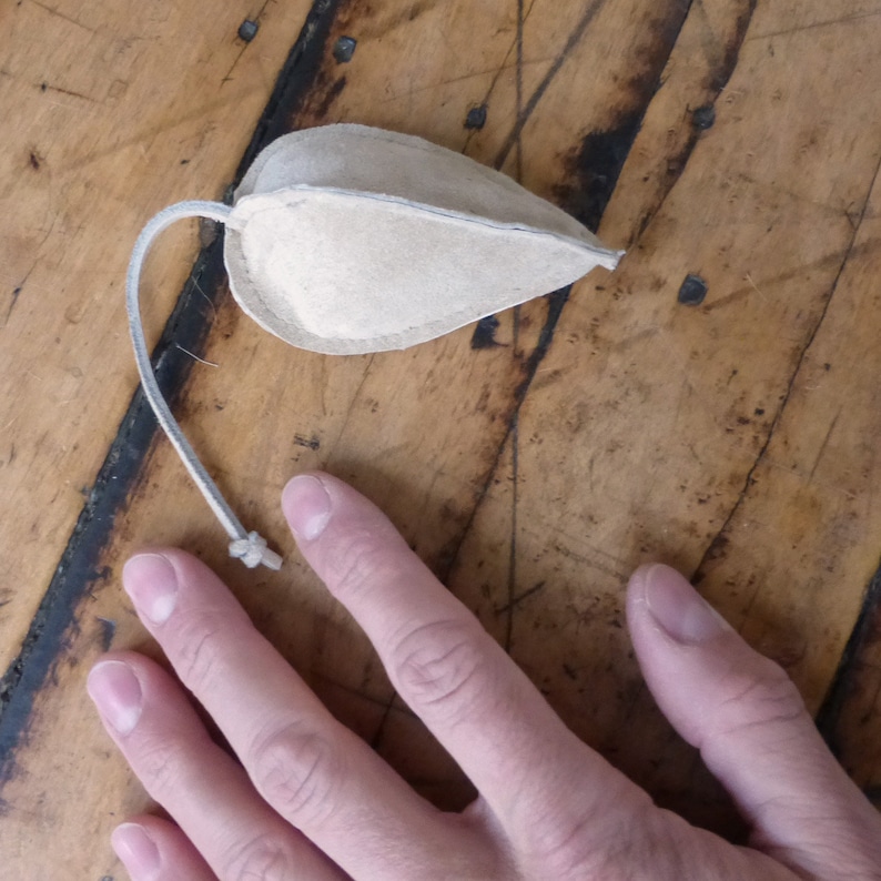 Puede incluir: Un juguete para gato de cuero marr&oacute;n en forma de rat&oacute;n con una cuerda larga.