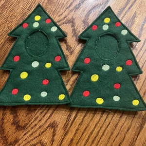 May include: Two green felt Christmas tree-shaped coasters with red, yellow, and green embroidered dots.