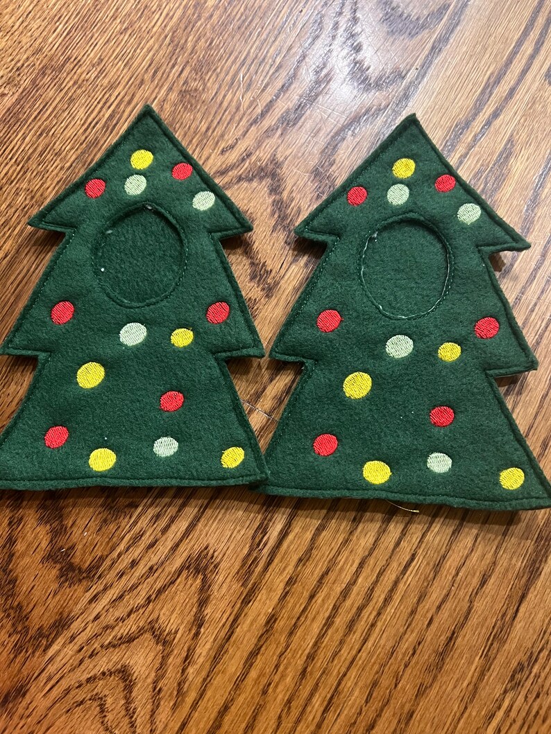 May include: Two green felt Christmas tree-shaped coasters with red, yellow, and green embroidered dots.