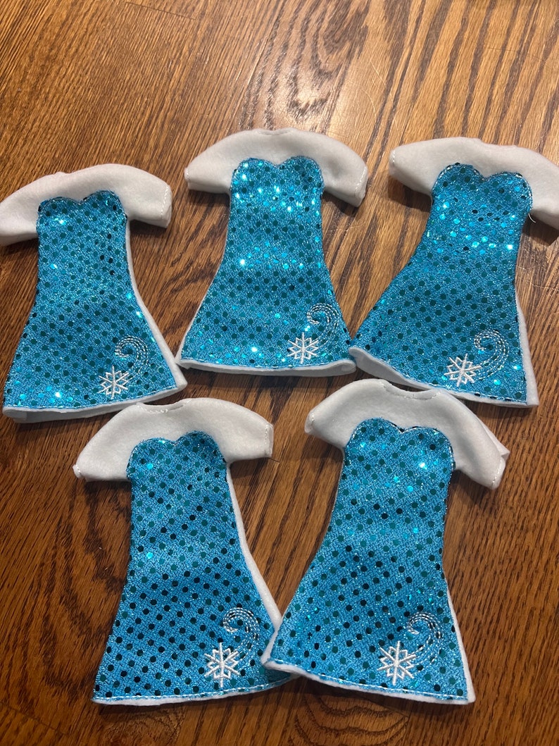 May include: Five blue and white sequined dresses with snowflake embroidery. The dresses are made of felt and have a white trim.