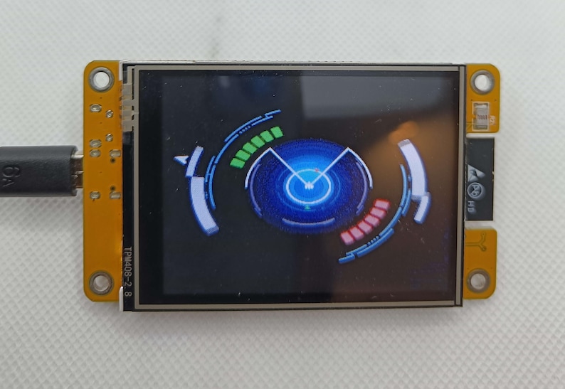 May include: A small, blue and black screen with a circular graphic displaying a blue circle with a white pointer and a green and red bar graph. The screen is mounted on a yellow circuit board with the text "TPMA02-2.8" printed on the side.