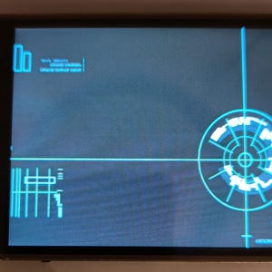 Può includere: Uno schermo radar blu e bianco con un display circolare che mostra una serie di cerchi concentrici e linee. Lo schermo è su uno sfondo nero e ha un sottile bordo nero. Il testo "WIFI: 192.168.1.100" è visualizzato nell'angolo in alto a sinistra dello schermo.