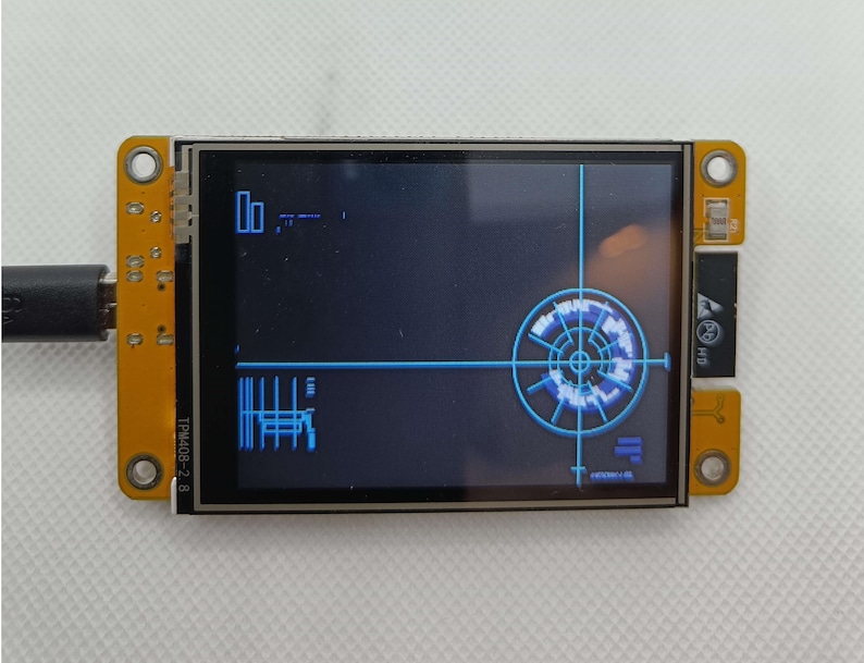 May include: A small, blue and black LCD screen with a circular graphic on the right side of the screen. The screen is mounted on a yellow circuit board with black connectors and the text "T-PIN40B-2.8" printed on the board.