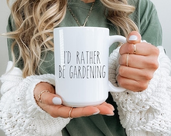 May include: White ceramic mug with black text that reads "I'd rather be gardening".