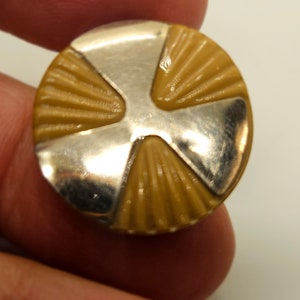 Puede incluir: Botón redondo con centro color beige y detalles metálicos plateados. La parte beige tiene un diseño acanalado en forma de abanico. El metal plateado forma una cruz en la superficie del botón. Ideal para costura o manualidades.