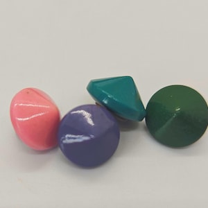 May include: Four colorful, decorative buttons in pink, purple, teal, and green. The buttons have a glossy finish and various shapes, including a rounded oval, a sphere, a pyramid, and a cone.