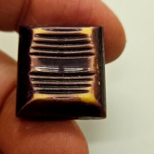 May include: A purple and yellow plastic button with a grooved design.