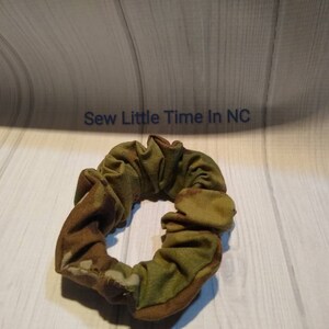 May include: A green, brown, and tan camouflage fabric scrunchie.