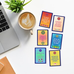 May include: Six colorful affirmation cards with a floral design and inspirational messages in German. The messages include "Ich umgebe mich mit Menschen und Dingen, die mir guttun", "Ich akzeptiere mich, mit all meinen St&auml;rken und Schw&auml;chen", "Ich gebe mir die Liebe, die ich mir immer gew&uuml;nscht habe", "Ich lasse alte Verletzungen los und &ouml;ffne mich f&uuml;r Heilung", "Ich erlaube mir, mich vollst&auml;ndig zu entspannen", and "Mein Leben ist ein Geschenk, und ich gestalte es mit Liebe und Hingabe".