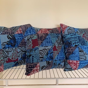 May include: Three blue and red patterned throw pillows with a geometric and floral design.